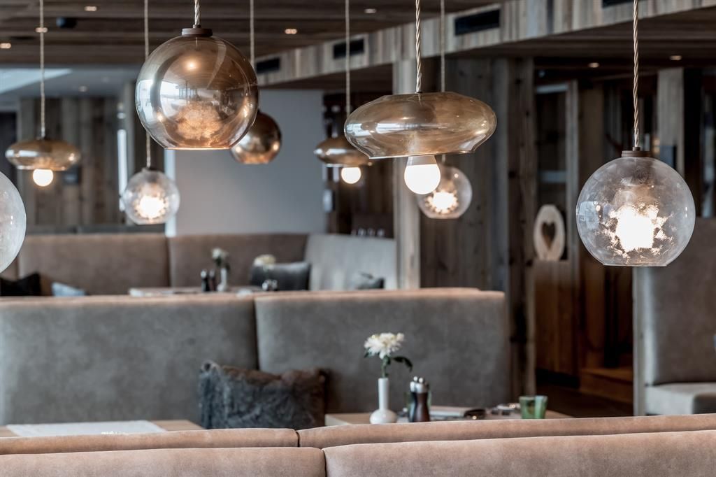 A stylish restaurant with modern light bulbs and cozy seating areas. The wood and gray tones create an inviting atmosphere.
