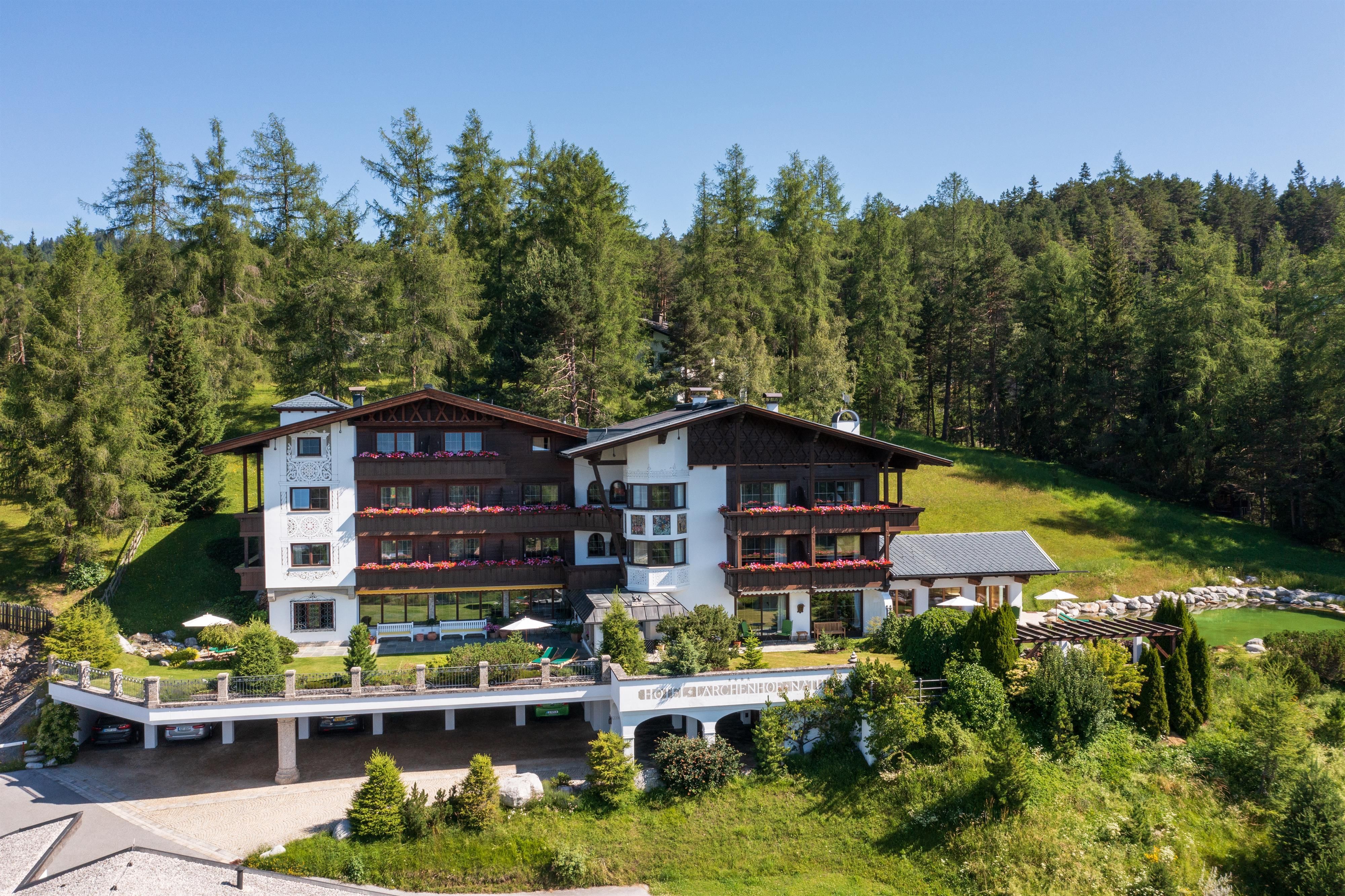 An idyllic hotel surrounded by green trees and gentle hills. The architecture is traditional and welcoming.