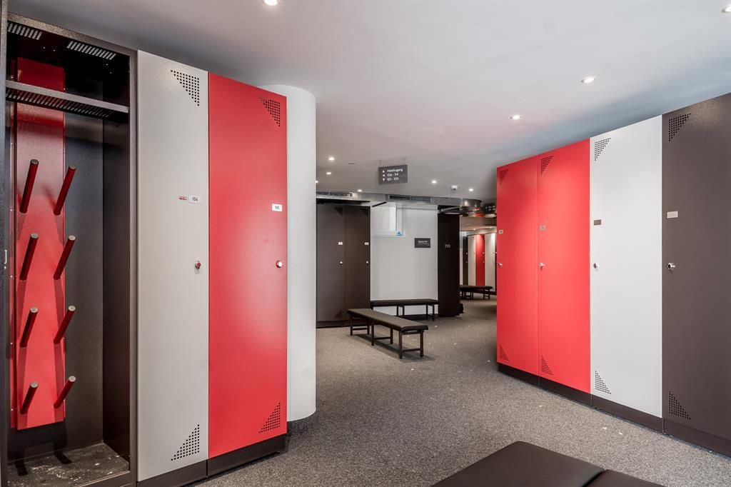 A modern changing area with red and gray lockers. The space is well-lit and has a clear, structured look.