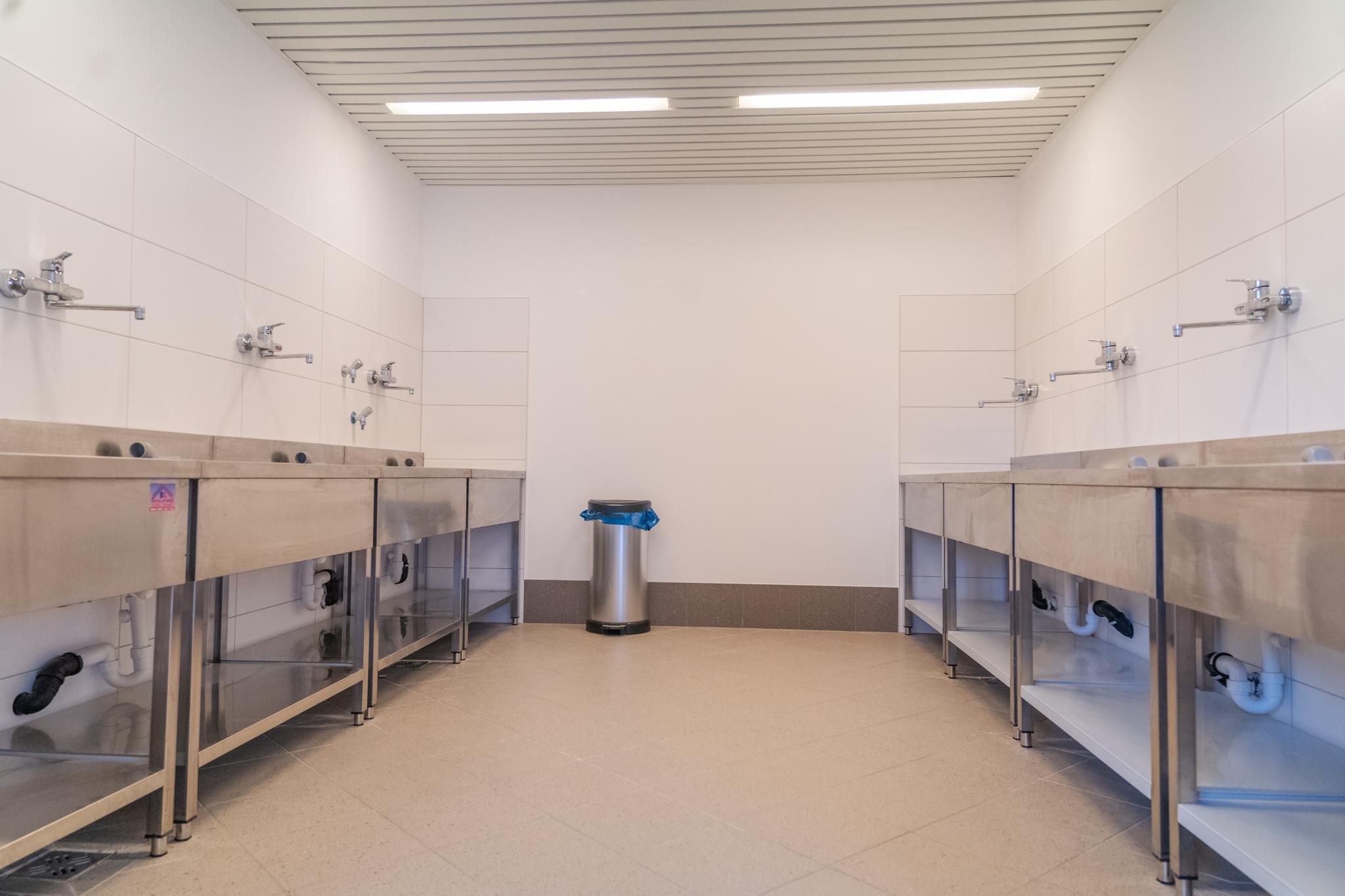 A clean washroom with a stainless steel sink. The room has bright walls and modern furnishings.