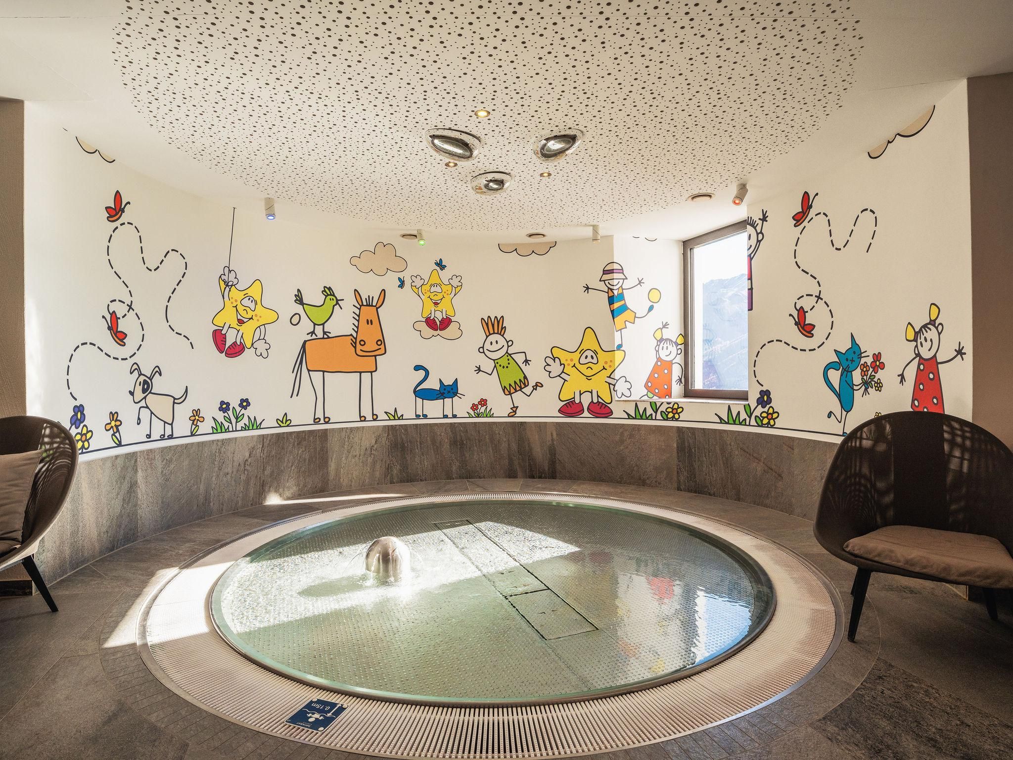 Round baby pool for the little ones with colorful children's motifs on the wall.