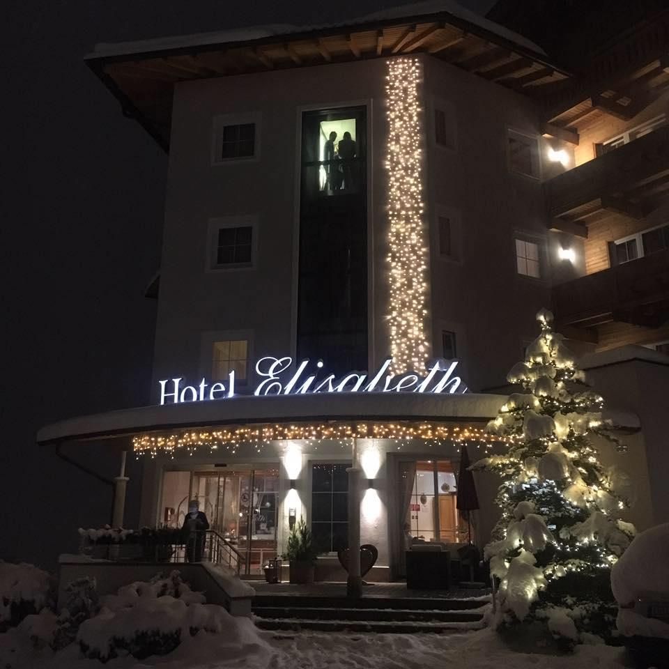 A charming hotel with festive lighting and a Christmas tree in the snow. The facade radiates a cozy atmosphere.