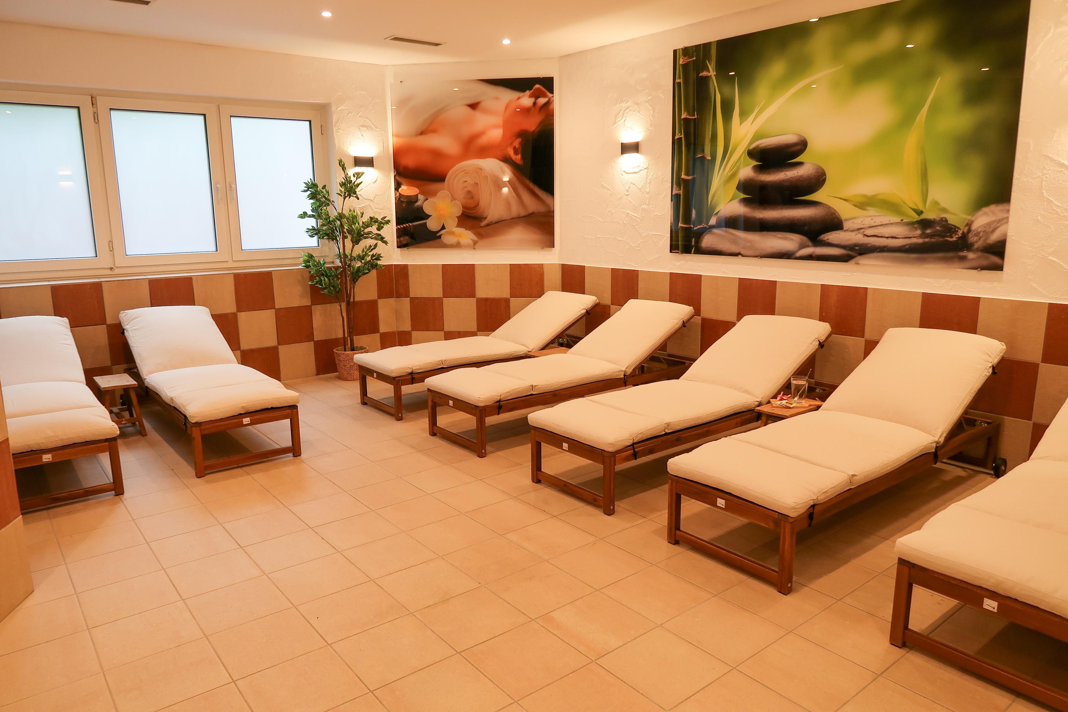 A relaxed wellness area with loungers and tranquil images. Soft lighting and plants create a pleasant atmosphere.
