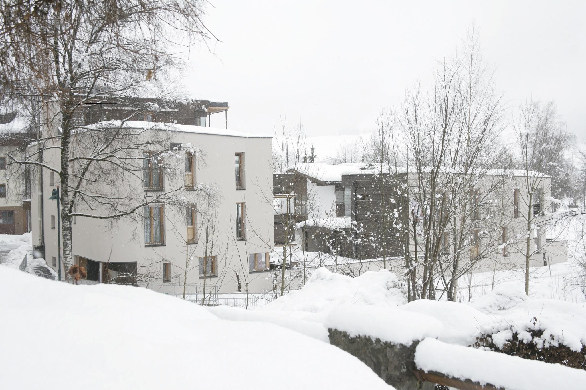 A modern building in a snowy landscape. The snow covers the ground and the surroundings, while the trees are lightly covered with snow.