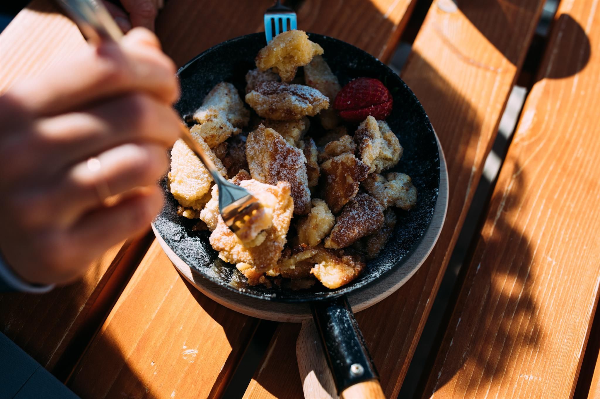 A plate with delicious, golden-brown pastry, garnished with fresh berries. A person is cutting into the dessert with a fork.