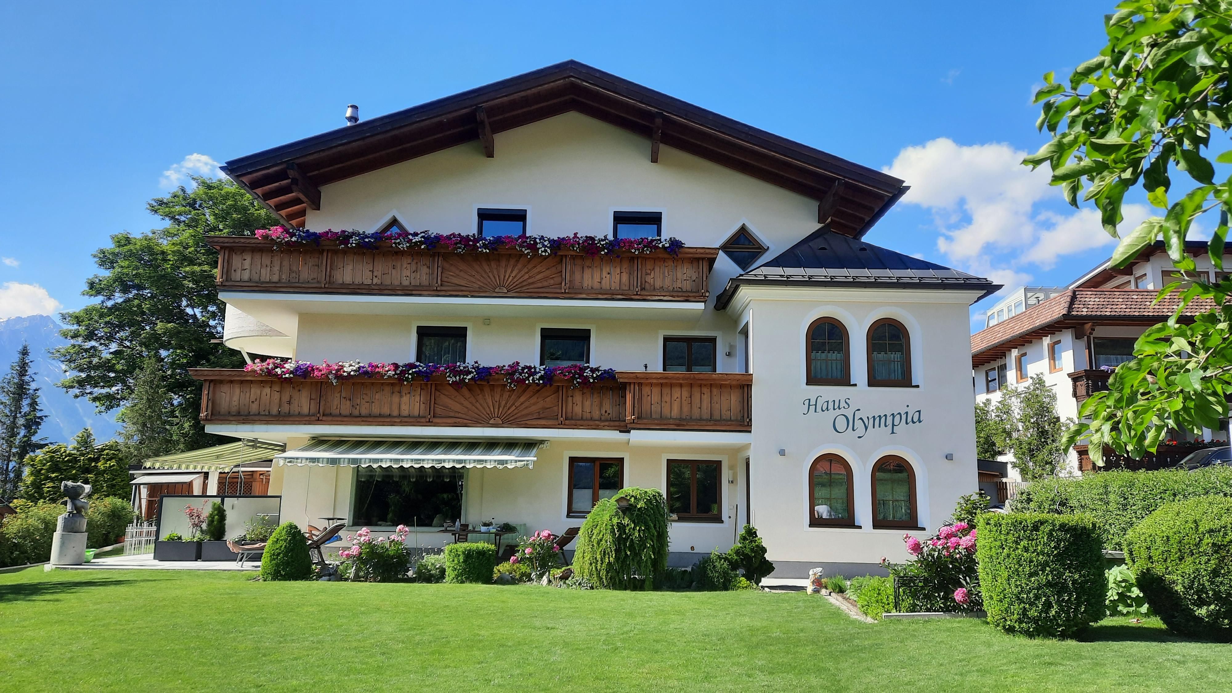 Exterior view of House Olympia with balconies and blooming flowers. The well-maintained garden is available for our guests.