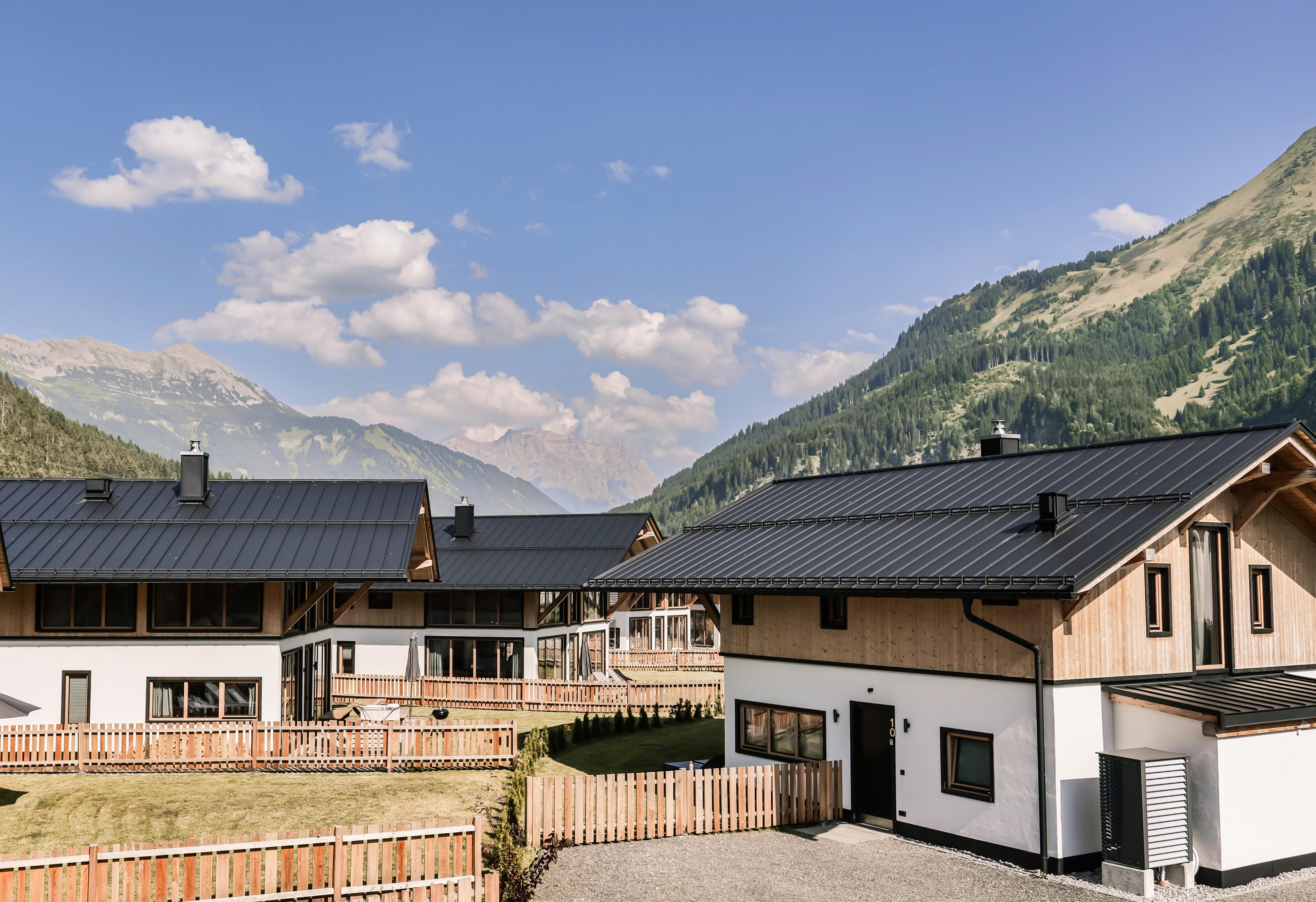 Modern houses in the mountains with a clear sky. The surroundings are green and inviting.