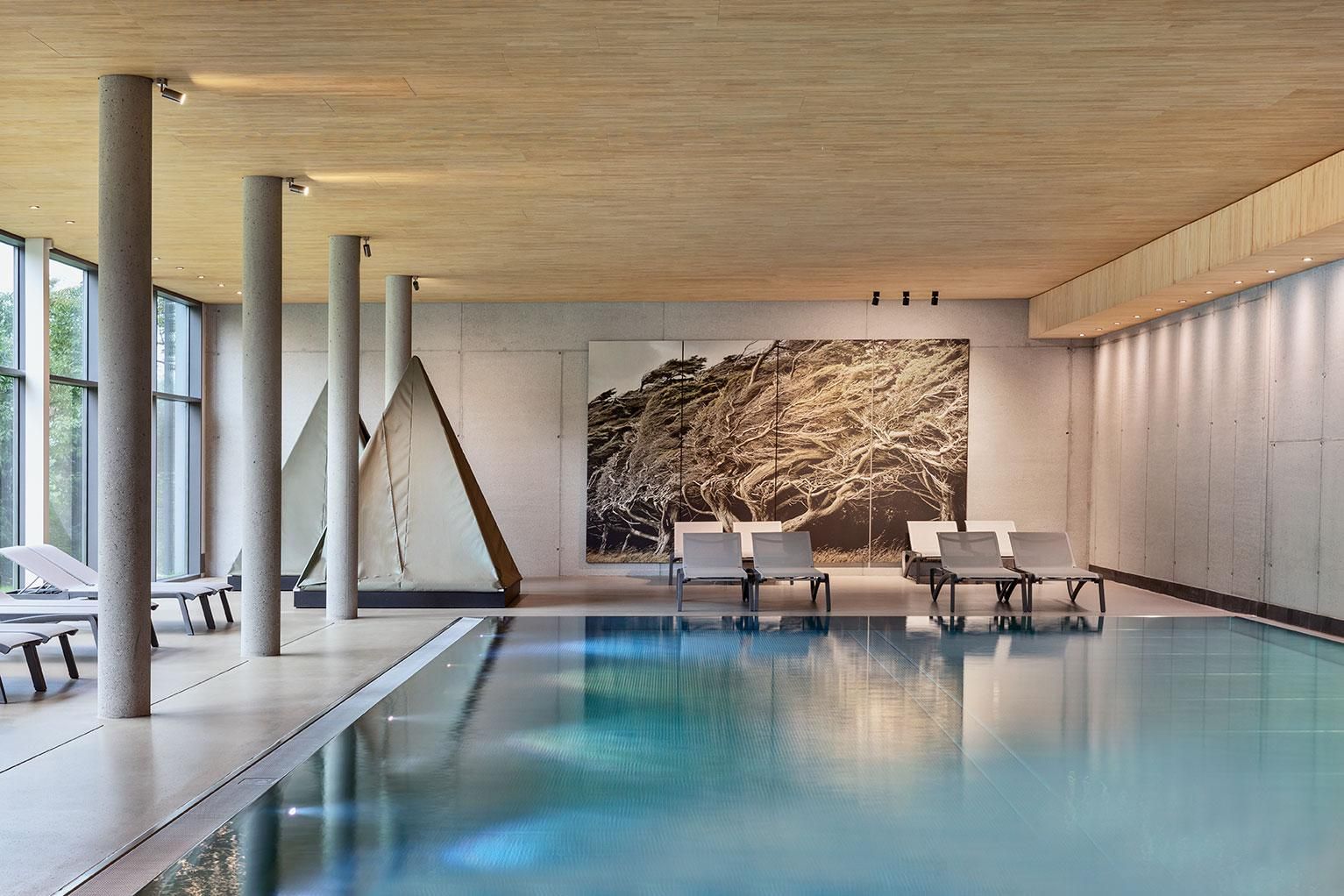 An elegant indoor pool with modern design and large windows. Relaxing loungers complement the serene atmosphere.
