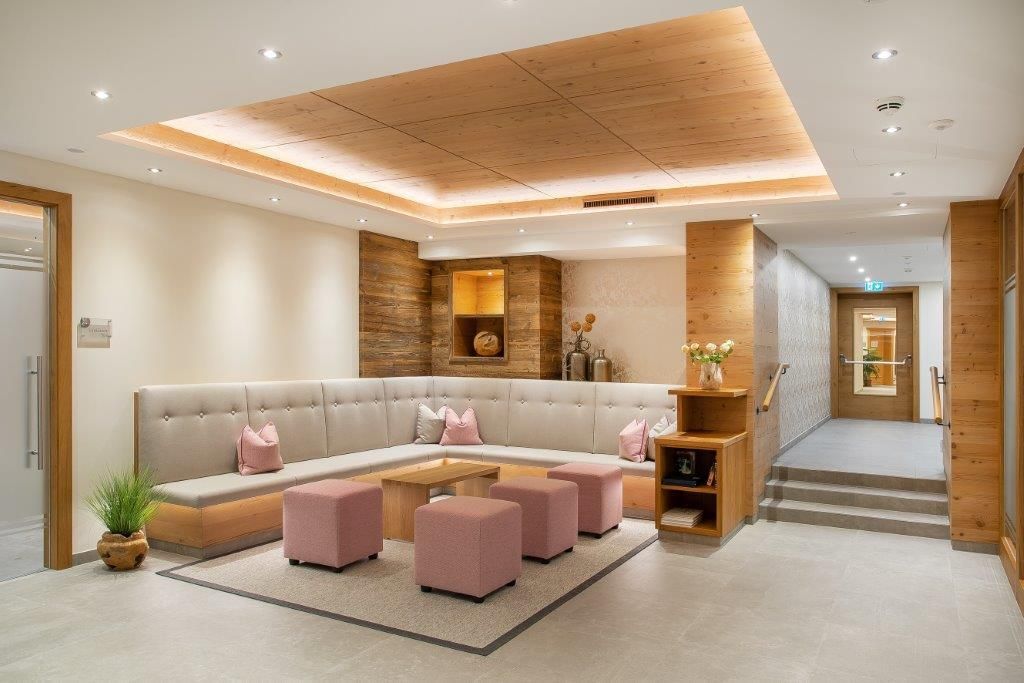 A modern lobby with a bright wood design. The seating area is inviting with pink stools and soft lighting.