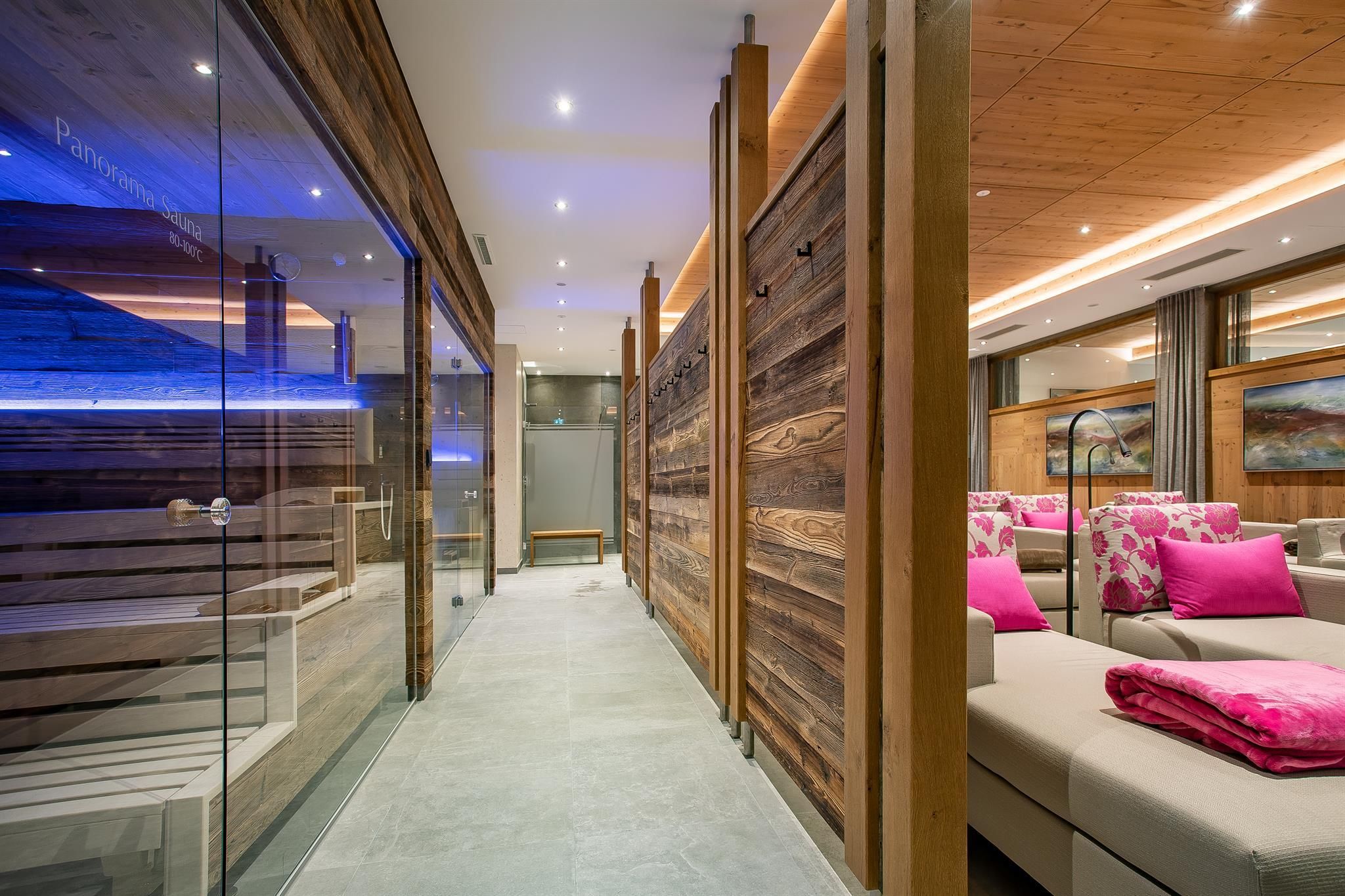 A modern wellness area with wooden paneling and cozy seating. The atmosphere is relaxing with soft lighting and colorful accents.