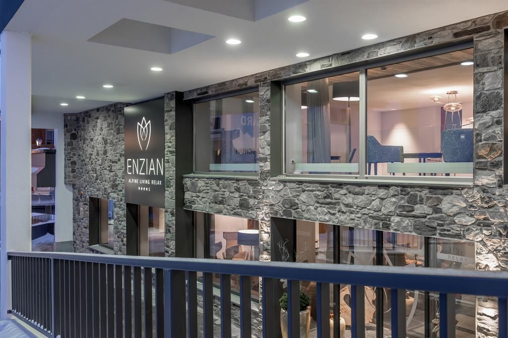 Modern building with stone facade and large windows. The inscription "ENZIAN" is clearly visible and invites entrance.