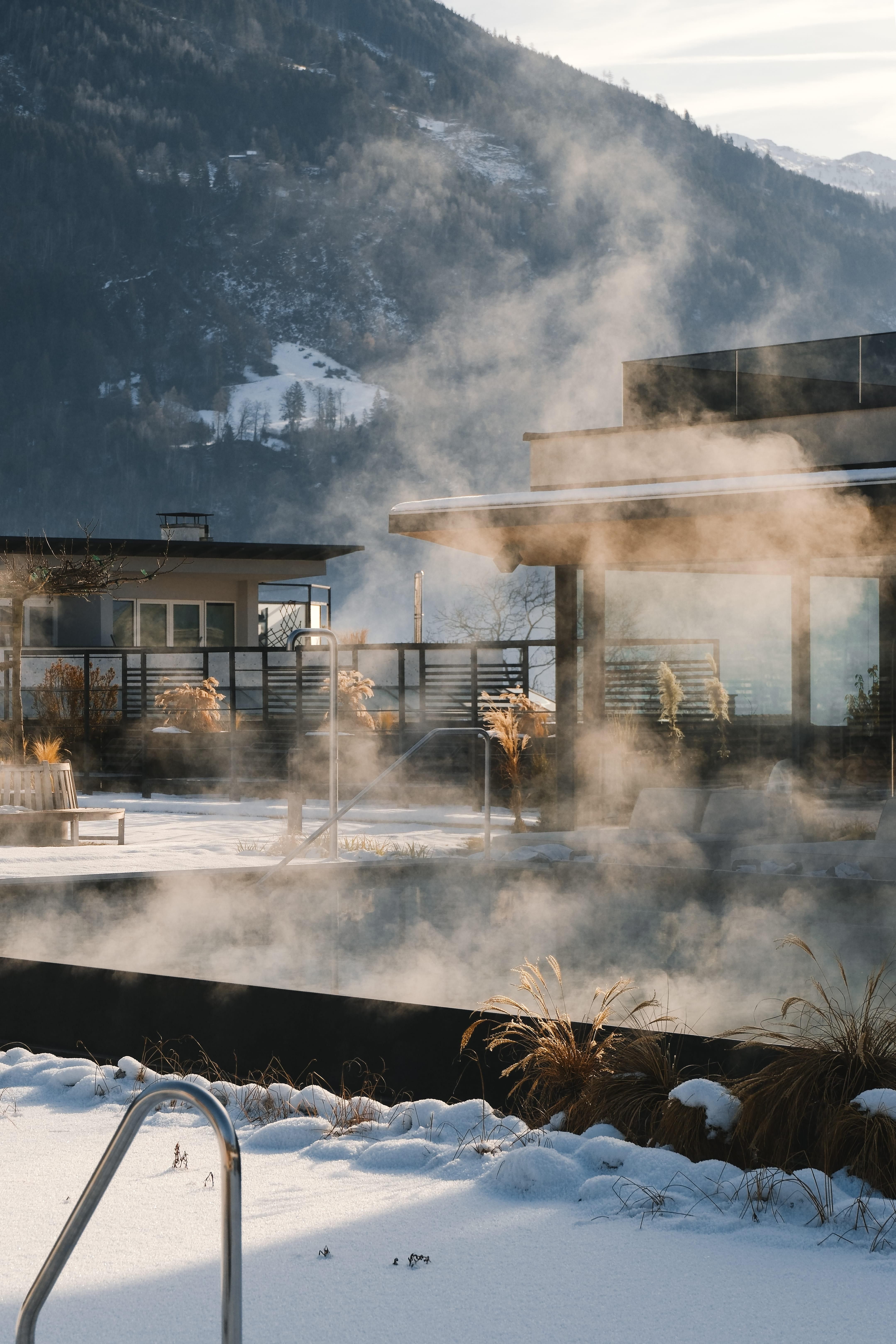 A modern terrace with steam clouds and a view of the mountains. The snow gives the scene a calm and wintry atmosphere.