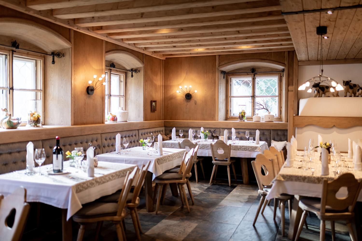 A cozy restaurant with wooden paneling and elegant tables. The windows let in plenty of light and create an inviting atmosphere.