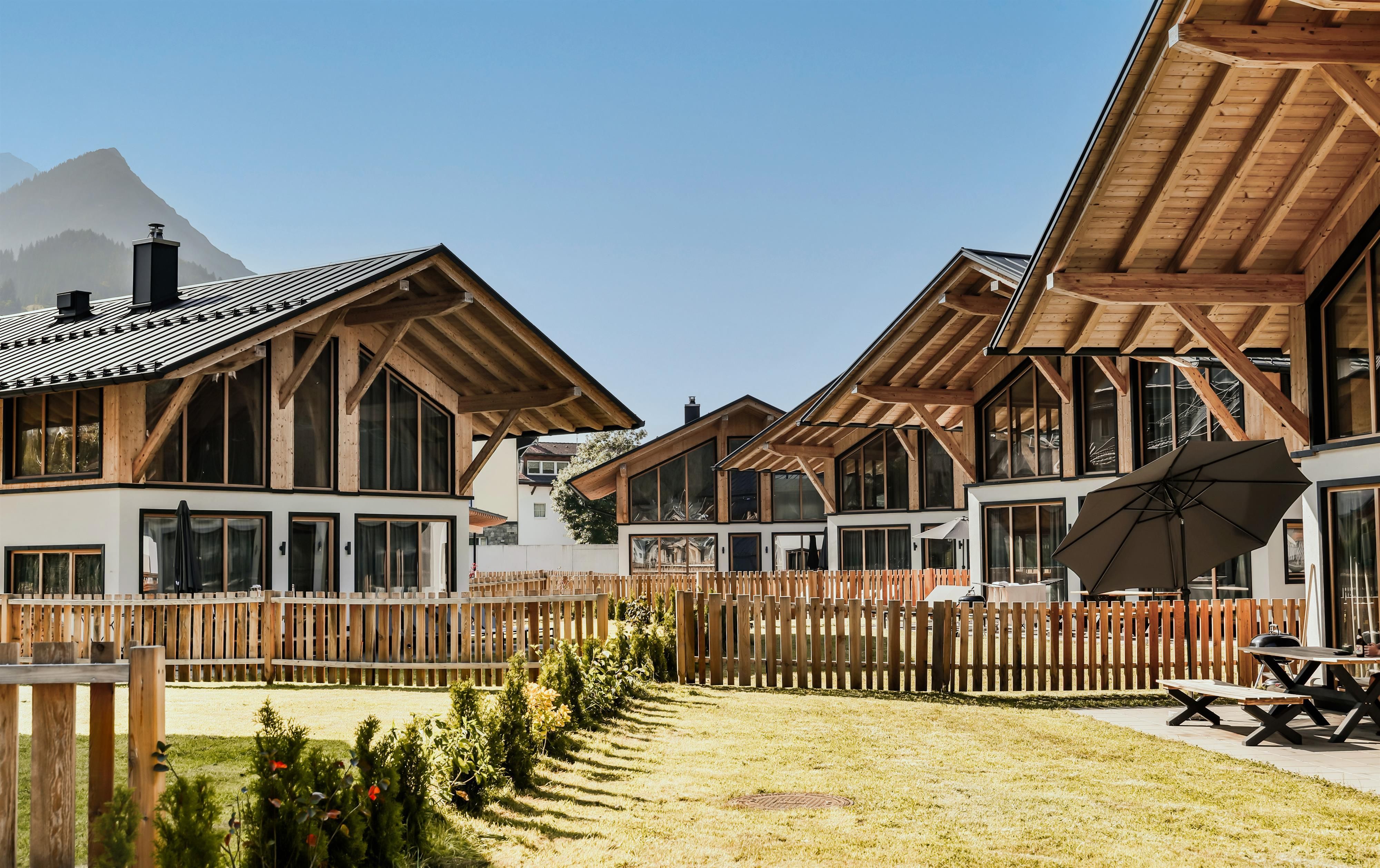 Modern wooden chalets with large windows in a quiet environment. The garden is well-kept and includes a cozy seating area.