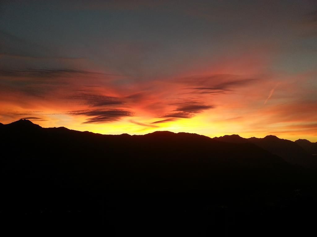 A breathtaking sunset over the mountains. The sky glows in vivid shades of orange and red.