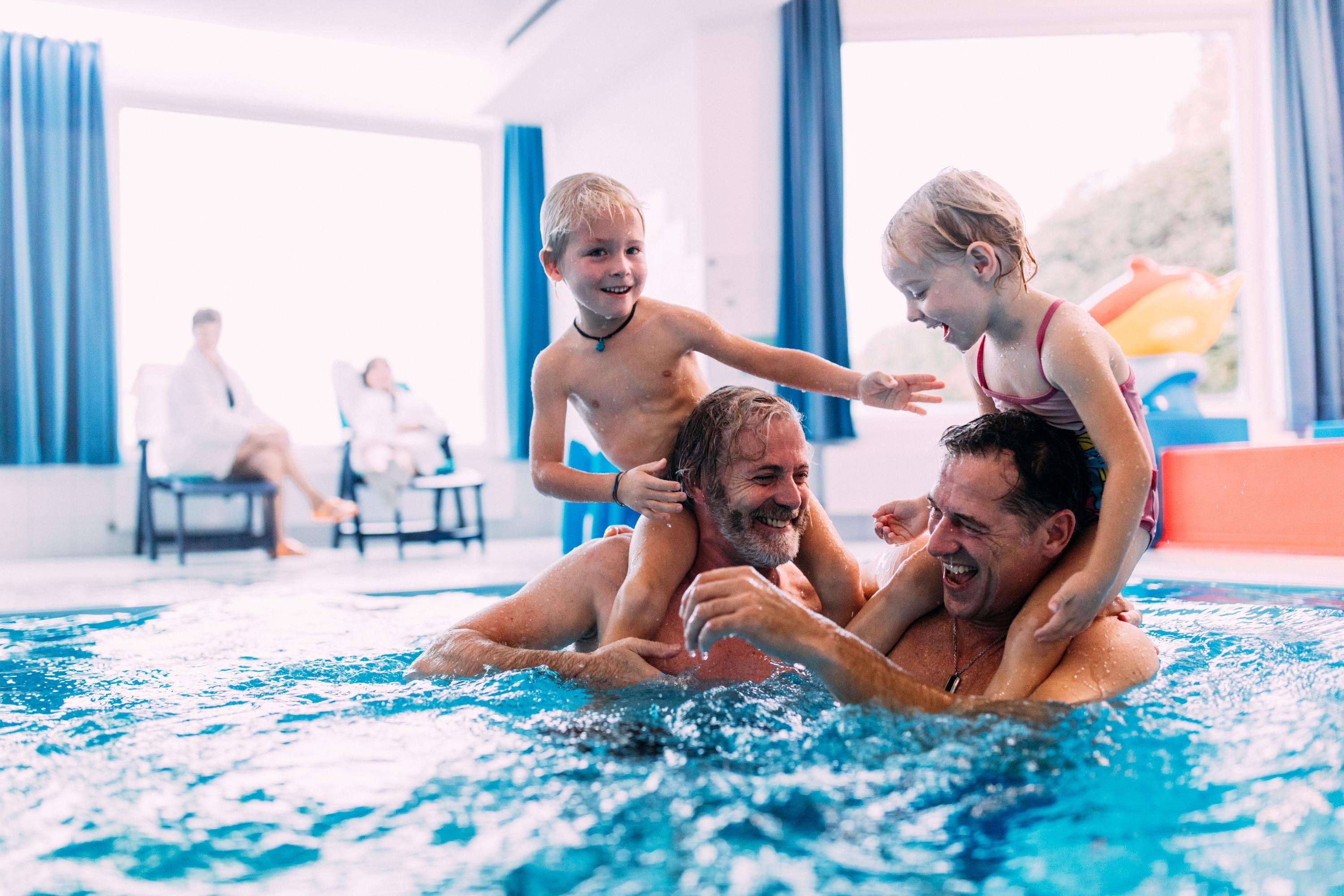A cheerful family bath in the pool with two adults and two children. Everyone is having fun and enjoying time together.