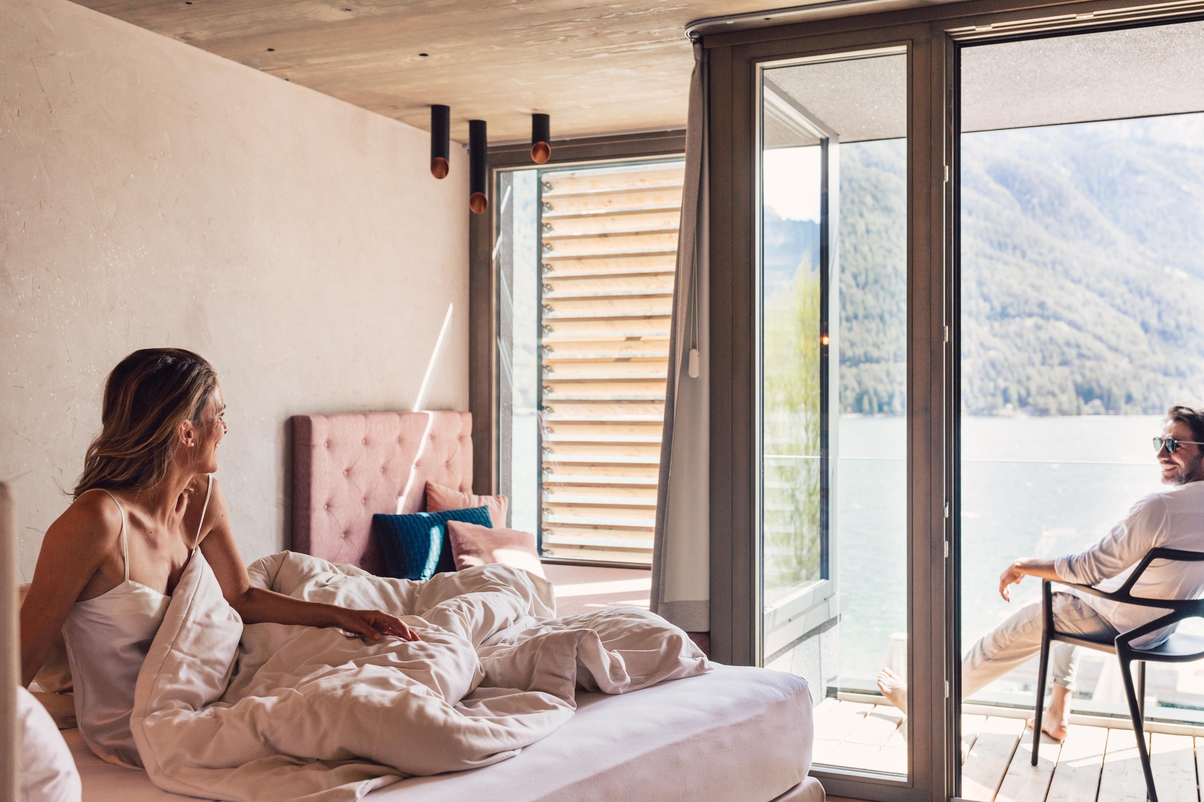 A cozy room with a view of the lake. A couple relaxes in bed and enjoys the view.