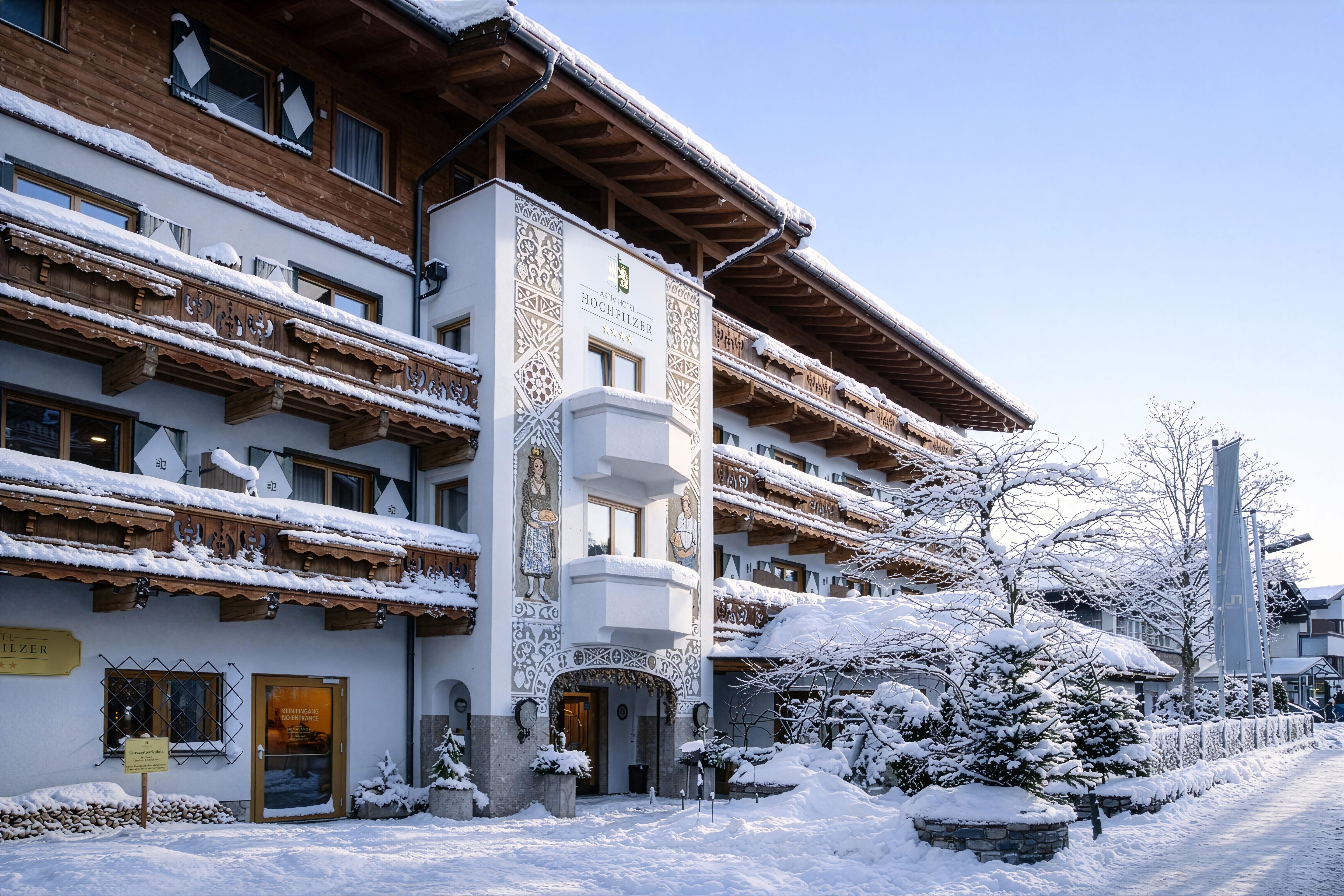 A charming hotel in winter with snow-covered balconies and decorative details. The surroundings are calm and idyllic, perfect for a relaxing stay.