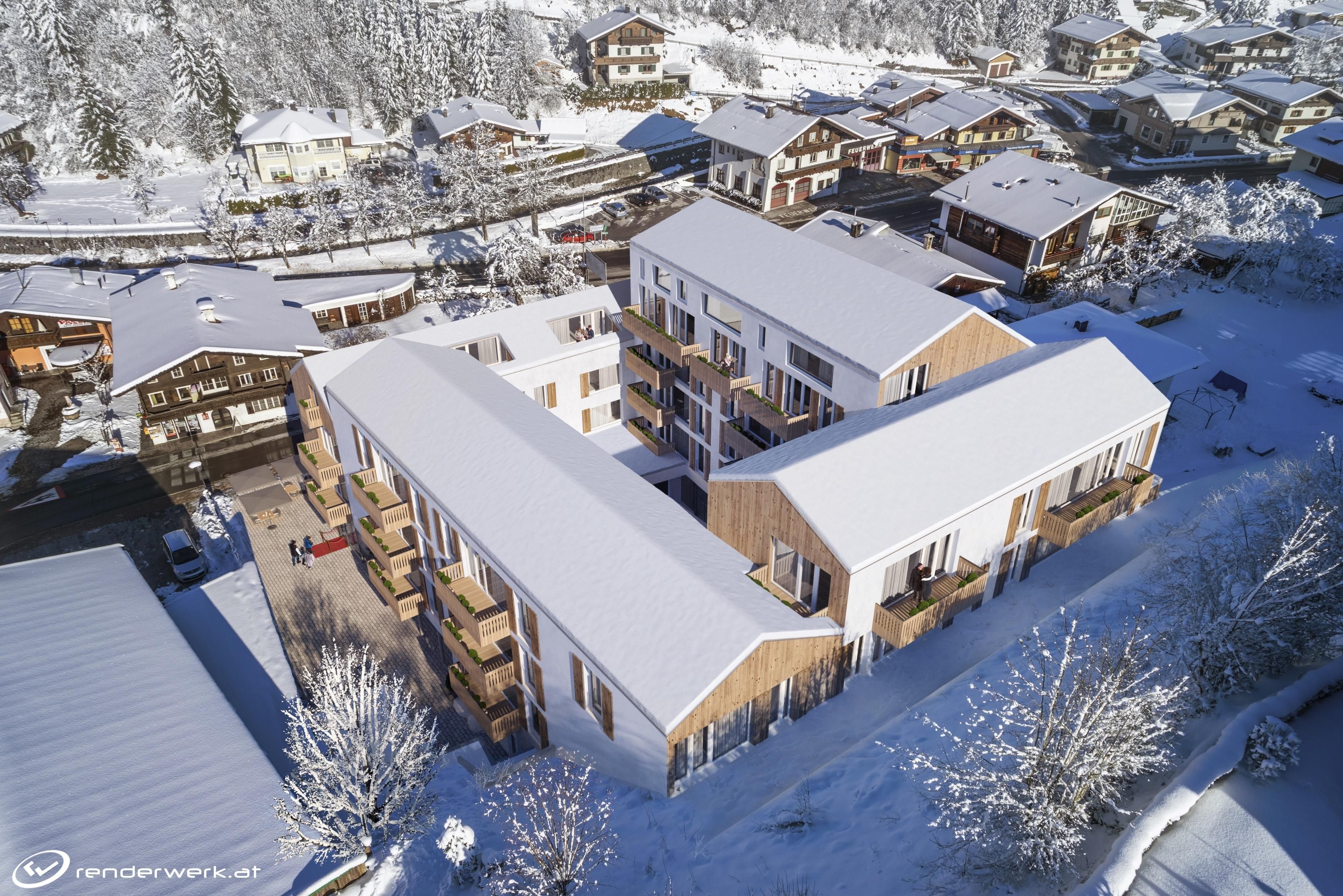 A snow-covered village with modern buildings and traditional chalets. The surroundings are idyllic and quiet in a wintry landscape.
