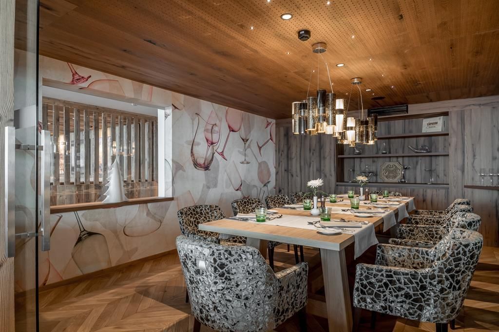 An elegant dining room with a large wooden table and stylish chairs. The walls are tastefully decorated and there is soft light from modern fixtures.