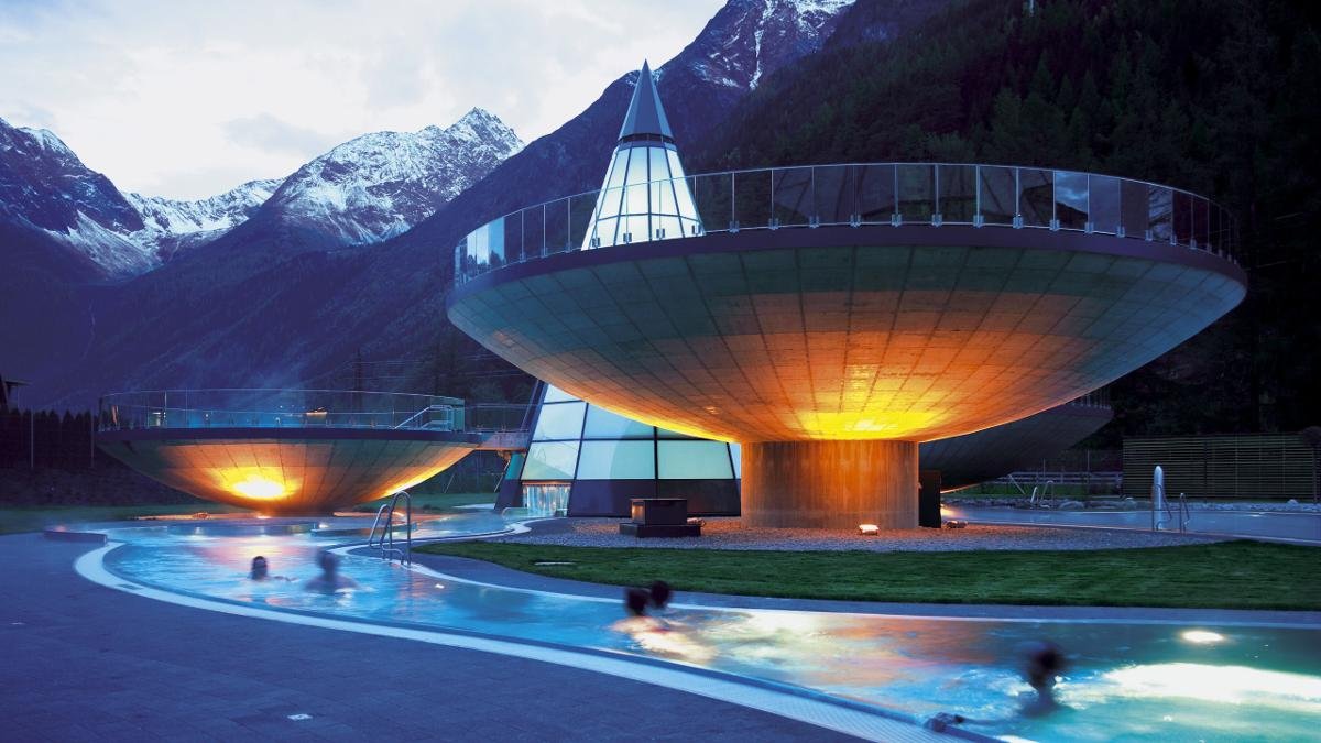 Tout autour d’une tour de verre en forme de cône où se reflètent les montagnes avoisinantes, les bassins extérieurs des thermes déploient leurs contours hémisphériques., © Ötztal Tourismus